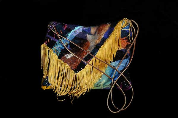 Purse made of colorful patchwork fabric and long, gold fringe on the closure flap.