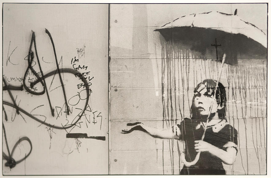 Silver print of girl under and umbrella next to a wall covered in graffiti