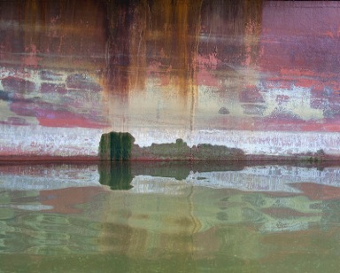 Encaustic painting with city surrounded by water and rusty sky above