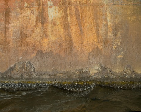 Painting of dark water and land beneath rust streaked sky