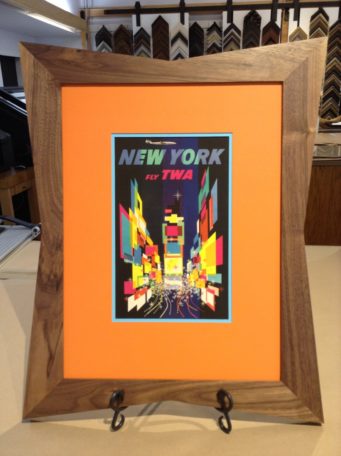 Colorful vintage TWA advertisement framed in mid-century modern wood frame and orange matting