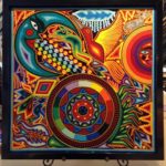 Brightly colored string art image of sun, moon, medicine wheel, maize, birds, and animals